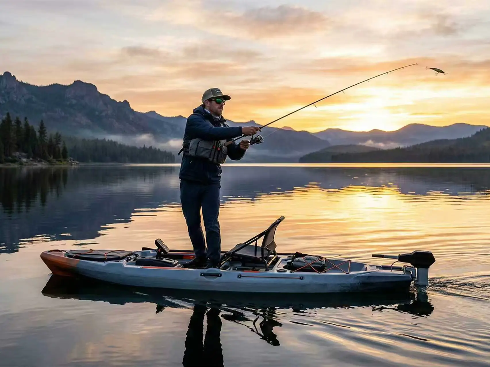 A kayak angler standing and casting on a calm lake at sunrise, demonstrating the stability of a well-equipped motorized kayak.