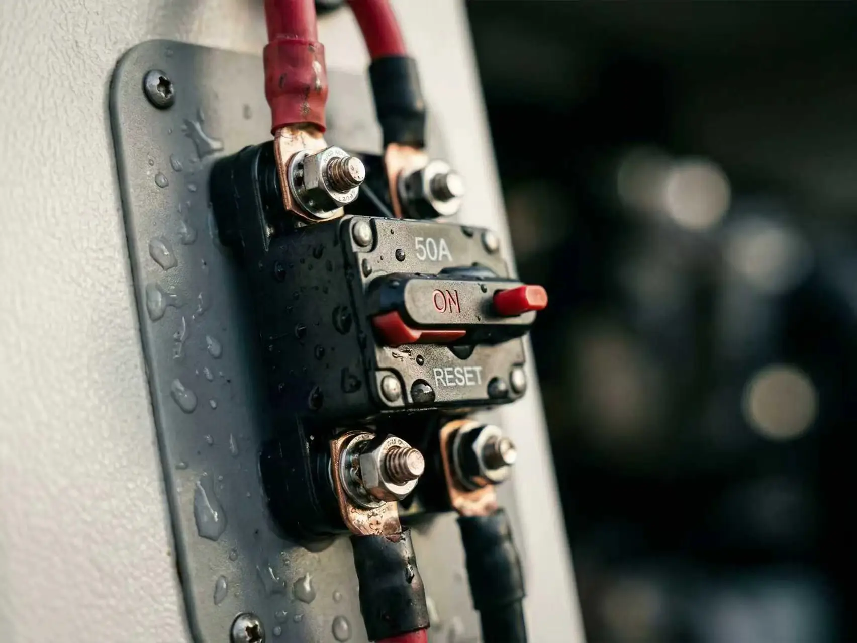 Close-up of a heavy-duty marine circuit breaker installed on a boat with thick gauge wiring for safety.