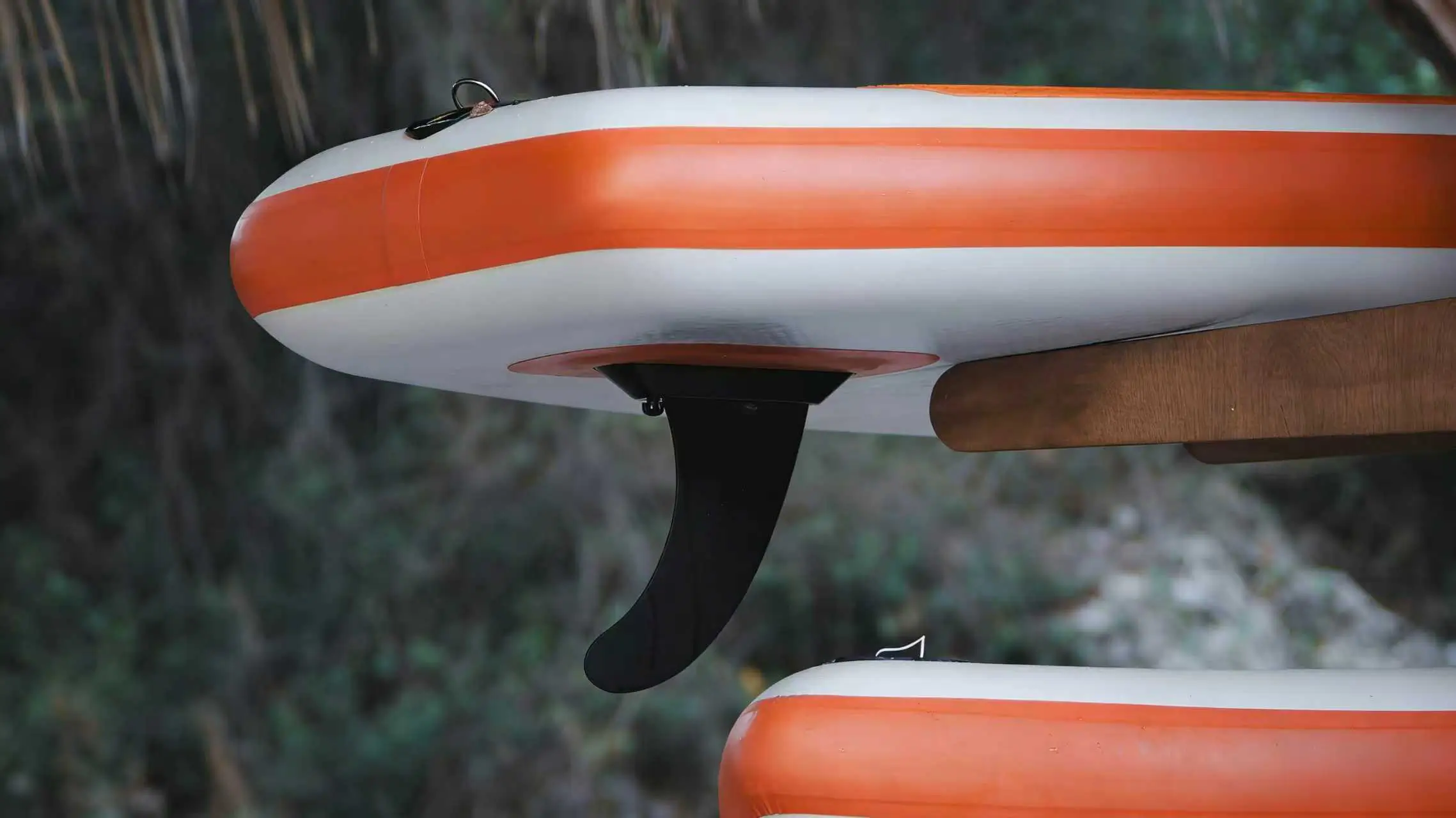 Close-up of a paddleboard fin setup, demonstrating the location for a slide-in electric fin motor installation.