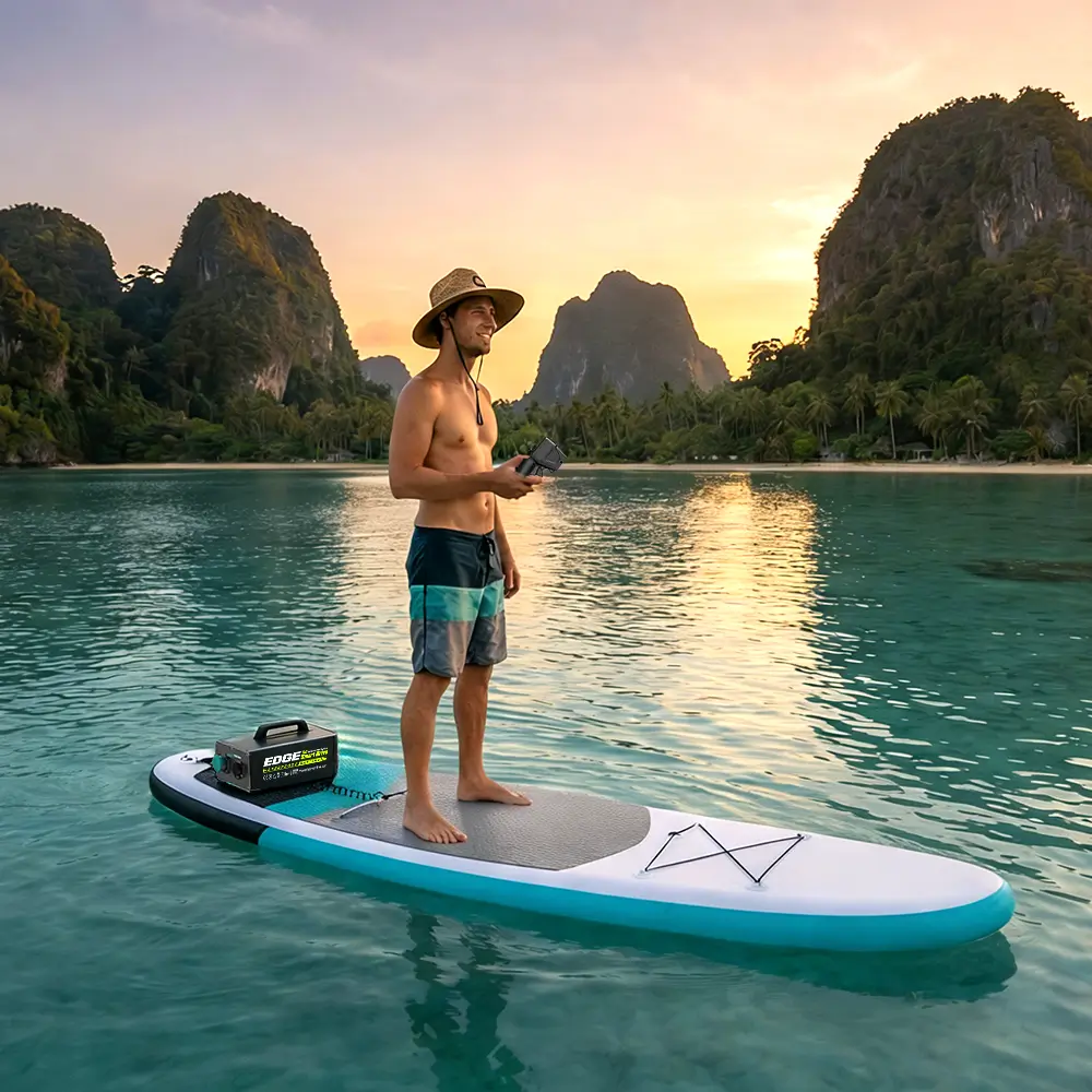 Man enjoying a sunset ride on a Stand Up Paddleboard (SUP) equipped with an EDGE K4 electric motor and battery box, holding the wireless remote control.