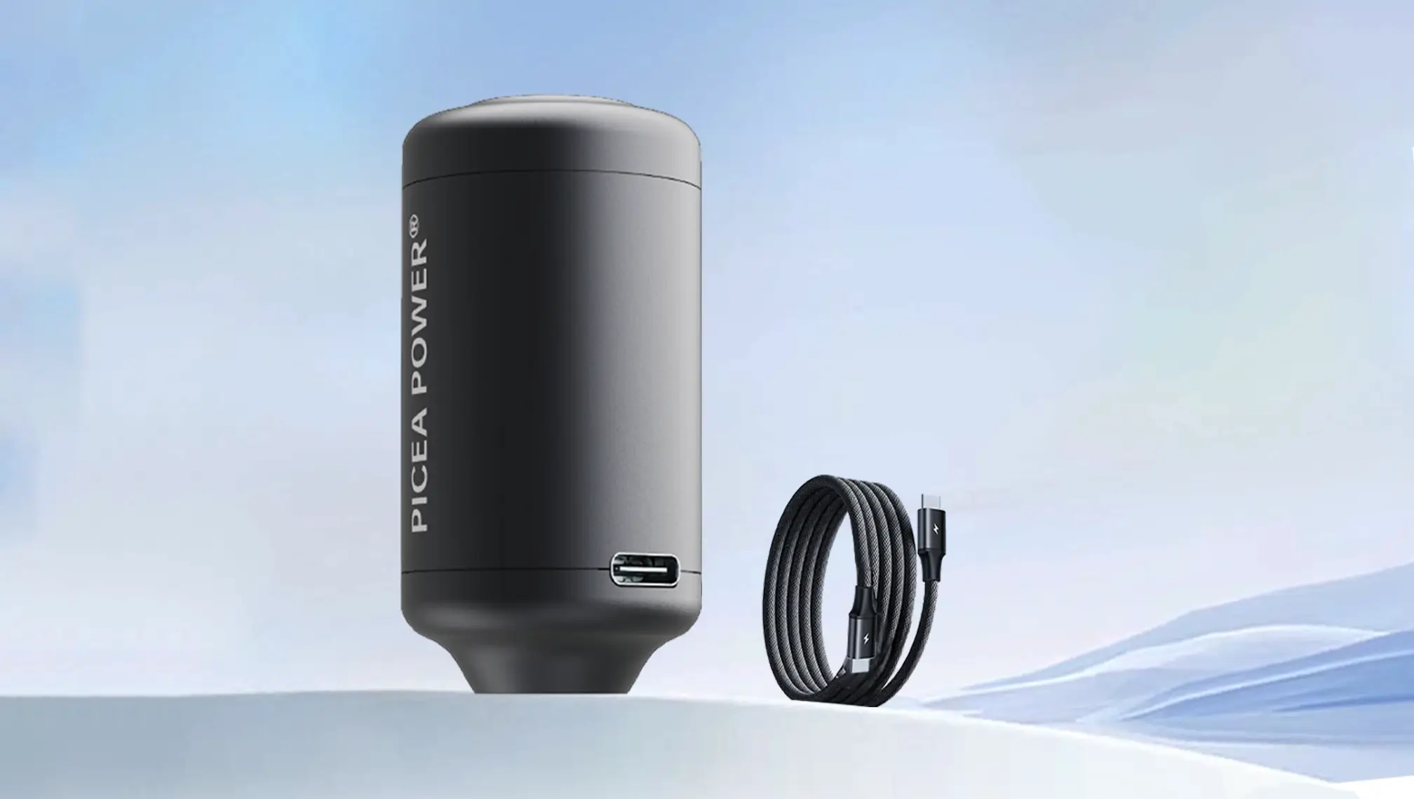 Black TEDGIX TurboBean mini air pump standing next to a durable braided USB-C power cable against a clean sky background.