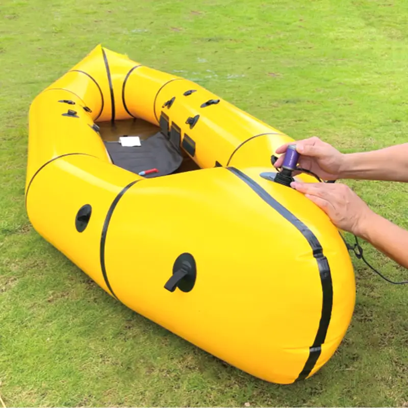 Outdoor scene showing TEDGIX TurboBean air pump inflating a large yellow packraft on the grass.