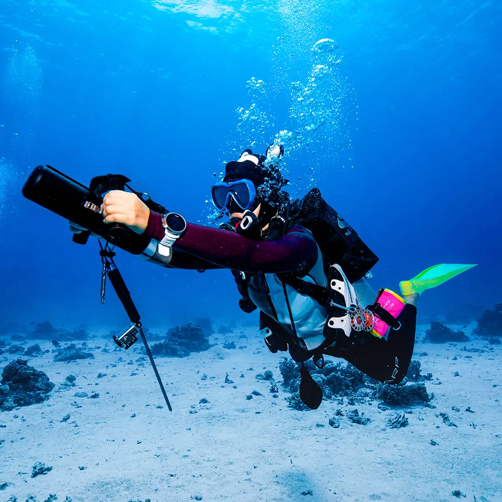 Scuba diver equipped with TEDGIX K5 underwater scooter cruising comfortably over the sandy ocean floor.