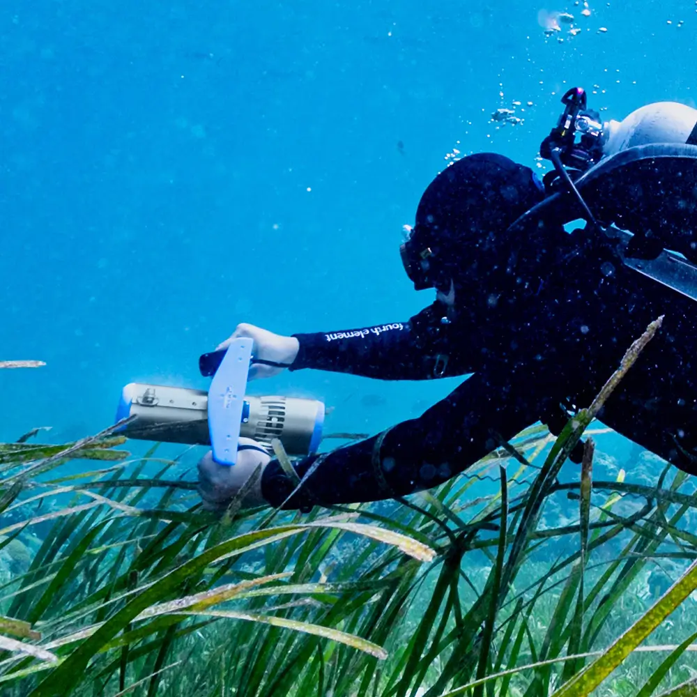 Close-up action shot of a diver maneuvering the TEDGIX K5 electric thruster through underwater currents.