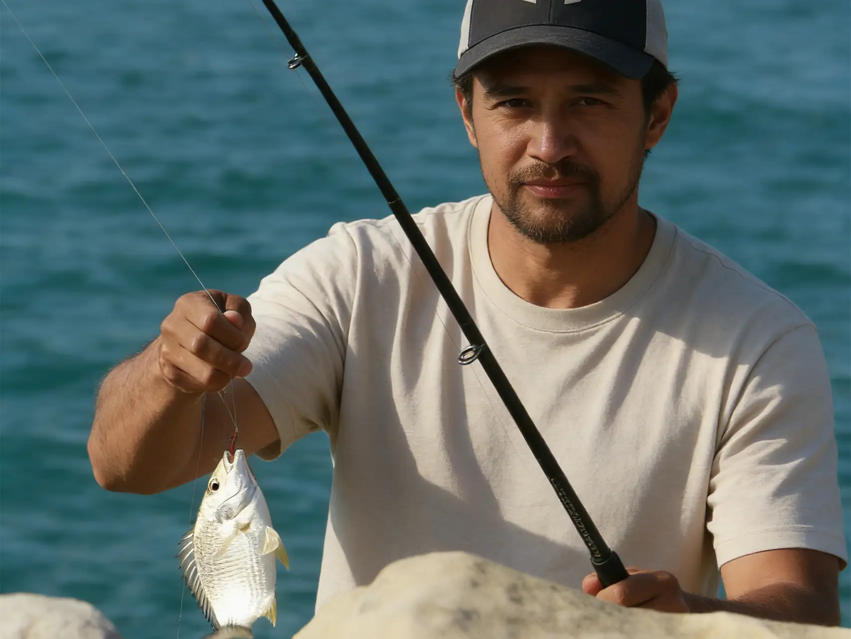 surfcaster fishing from rocks with a spinning rod near the ocean